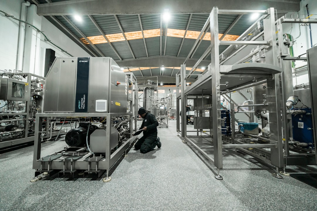 A worker repairs machinery in a factory setting.