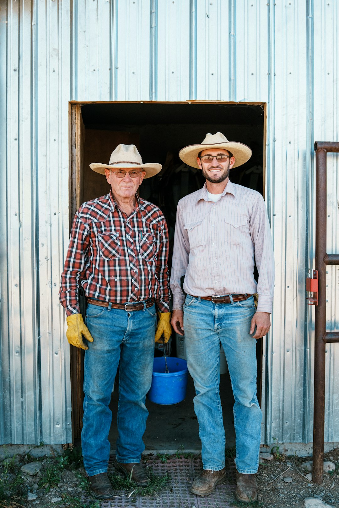 Two farmers wearing straw hats stand in a doorway.