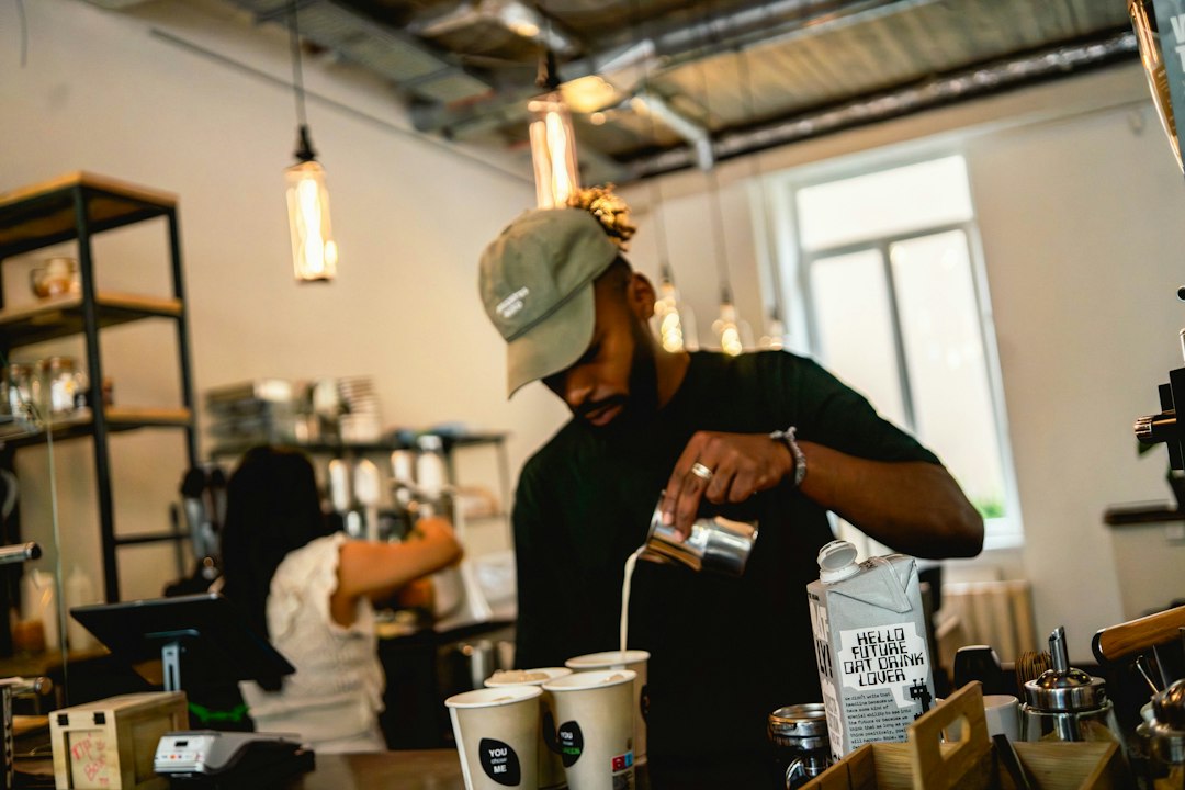 Barista pouring milk into coffee cups at cafe